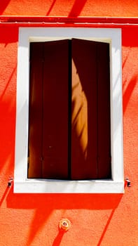 wooden Window with white frame in Burano on orange color wall building architecture, Venice, Italy