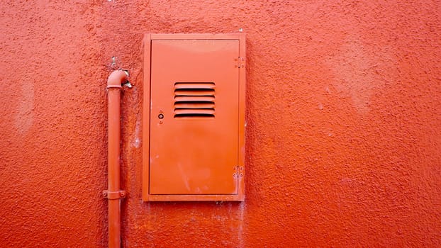 metal pipe and electric box on orange color wall in Burano, Venice, Italy