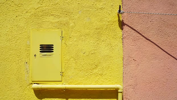 metal pipe and electric box on yellow color wall in Burano, Venice, Italy