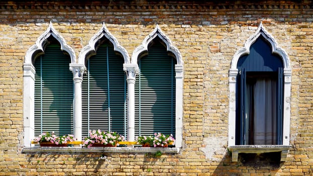 four windows in arch shape and ancient decay brick wall building architecture in Murano, Venice, Italy