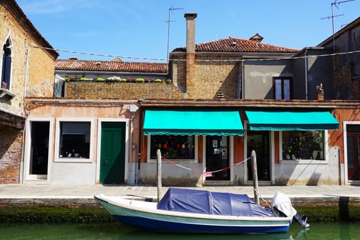 front building architecture with canal and boat in Murano, Venice, Italy