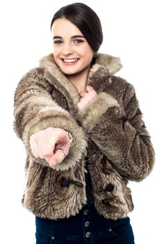 Smiling girl in fur coat, pointing her finger forward.