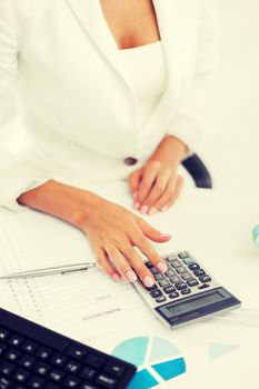 business, office, tax, school and education concept - woman hand with calculator and papers