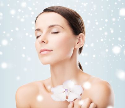 health and beauty concept - relaxed woman with orhid flower