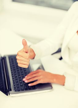 office, business, technology and internet concept - businesswoman with laptop computer showing thumbs up