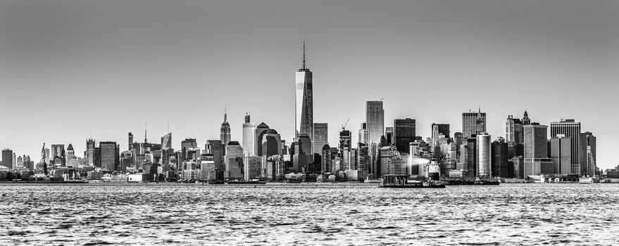 New York City Manhattan downtown skyline at dusk with skyscrapers illuminated over Hudson River panorama. Horizontal composition, copy space. Black and white image.