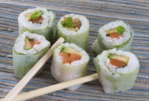 Delicious sushi rolls on white plate with chopsticks