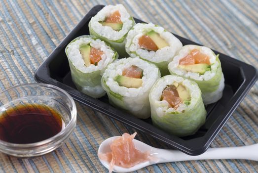 Delicious sushi rolls on white plate with soy sauce