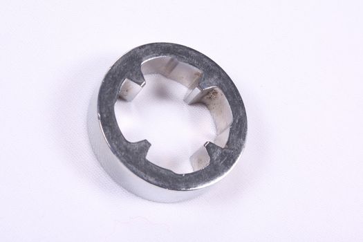 A broach made of steel used as a part in automobiles, on white fabric background.