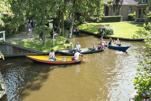 GIETHOORN, NETHERLANDS - JULY 18, 2015: Unknown tourists on boating trip in a canal in Giethoorn on july 18 2015. The beautiful houses and gardening city is know as "Venice of the North"