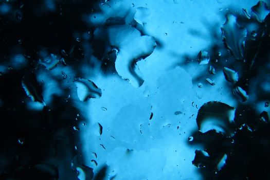 A background with the blue glass on a car with raindrops on it.                               