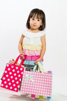 Asian Chinese little girl with shopping bag in white isolated background.