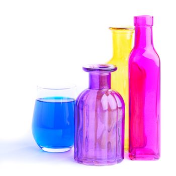 Three colorful bottles and one glass, isolated on white background