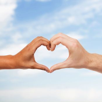 love and relationships concept - closeup of woman and man hands showing heart shape