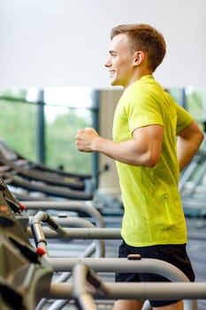 sport, fitness, lifestyle, technology and people concept - smiling man exercising on treadmill in gym