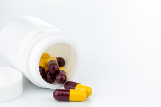 brown and yellow pills an pill bottle on white background (Isolated)
