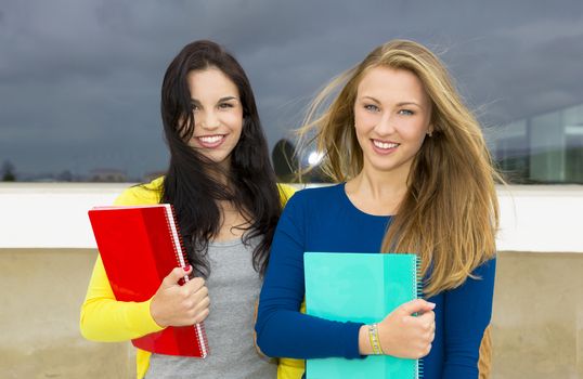 Two beautiful teenage students holding backpacks and smiling