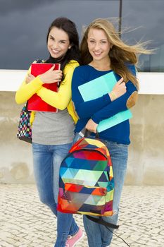 Two beautiful teenage students holding backpacks and smiling