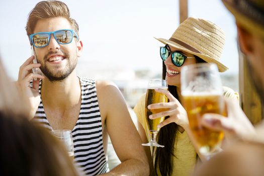 Friends having fun and drinking a cold beer at the beach bar