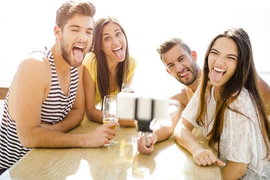 Group of friends at the beach bar and making a selfie