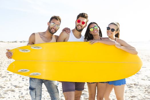 Group of friends together and holding a surfboard