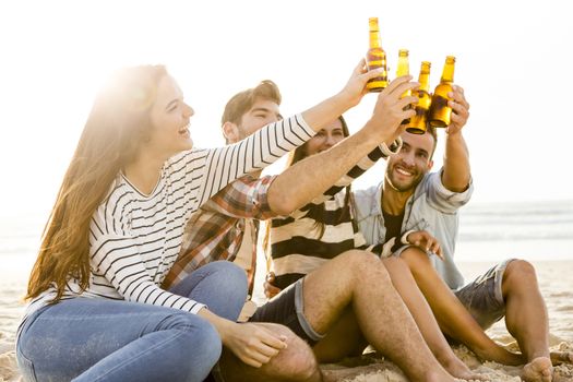 Friends having fun together at the beach and drinking a cold beer