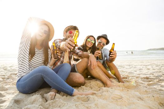 Friends having fun together at the beach and drinking a cold beer