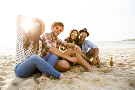 Friends having fun together at the beach and drinking a cold beer