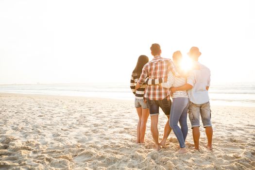 Group of friends at the beach and watching the sunset