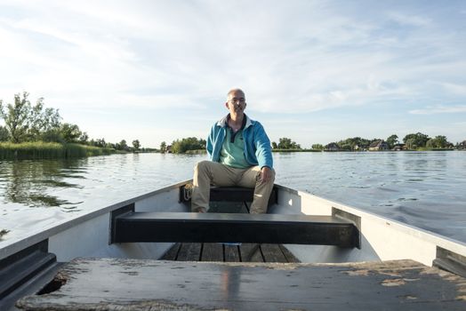man on wooden boat on lake in the netherlands