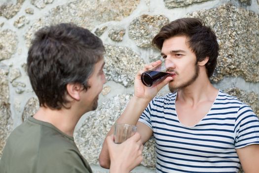 two friends having a drink and talking outdoors