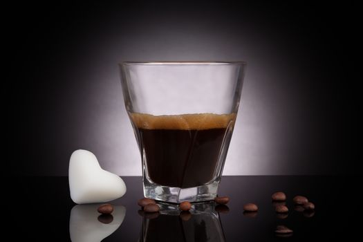 Espresso in glass, coffee beans and coconut oil in heart shape on dark background. Superdrink .Coffee and coconut oil.
