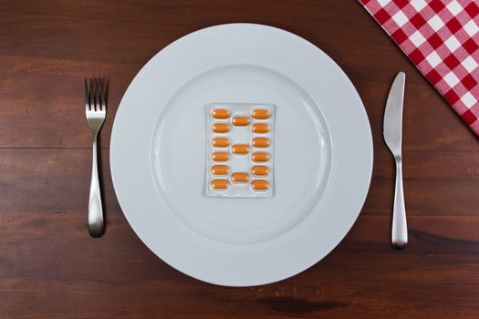 white dish with cutlery and pills on wooden table