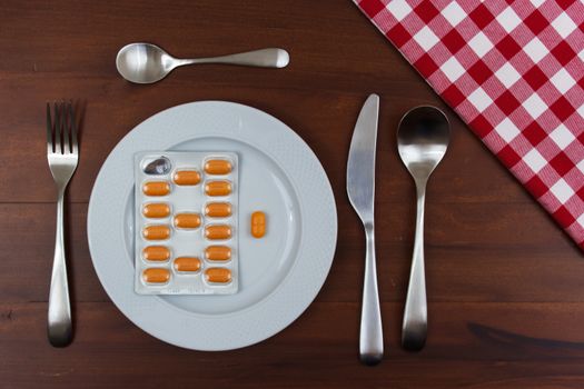 white dish with cutlery and pills on wooden table