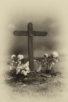 grave with flowers black and white and cross