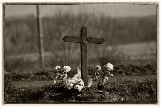 grave with flowers black and white and cross