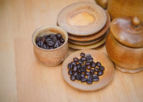 Coffee beans, cup of coffee and teapot on wooden desk. Set of cafe