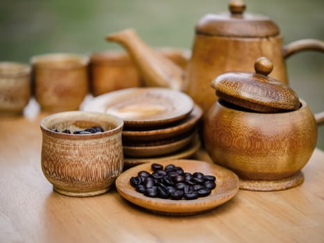 Coffee beans, cup of coffee and teapot on wooden desk. Set of cafe