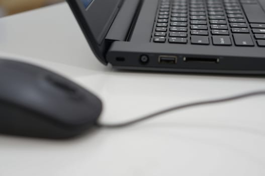 Keyboard and computer mouse are black color on desk at office.                                