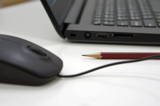 Pencil, computer and mouse placed on desk at office.                                