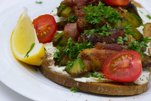 A slice of toasted bread with avocado wrapped with bacon on white plate