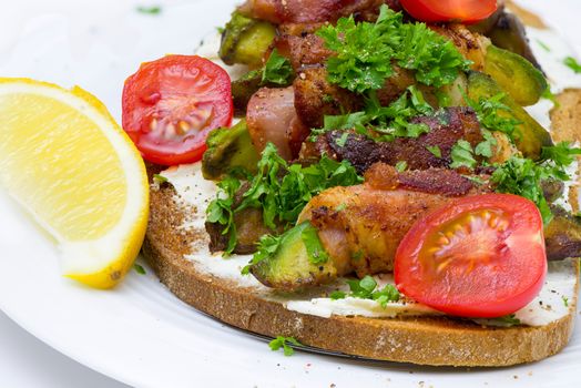 A slice of toasted bread with avocado wrapped with bacon on white plate