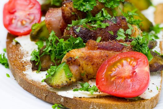 A slice of toasted bread with avocado wrapped with bacon on white plate