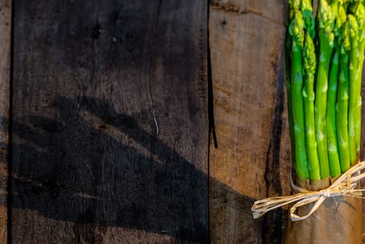 Bunch of fresh green asparagus spears tied om wood table