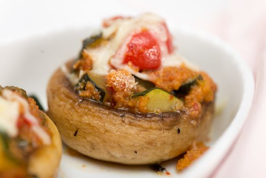 Mushrooms stuffed with vegetables and cheese on white plate