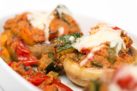 Mushrooms stuffed with vegetables and cheese on white plate