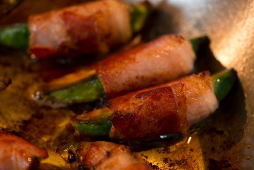 fried avocado pieces wrapped in bacon in a pan