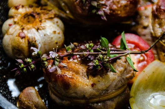 Closeup of pork tenderloin medallions with onion tomatoes garlic and pepper in a pan