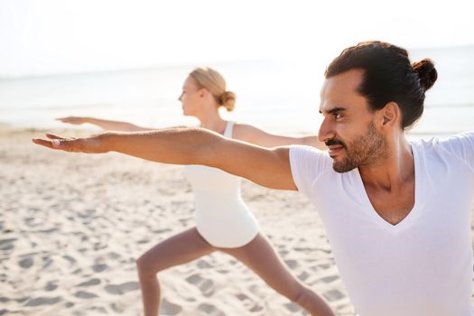 fitness, sport, friendship and lifestyle concept - close up of couple making yoga exercises on beach