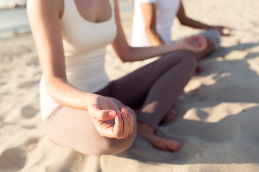 fitness, sport, people and lifestyle concept - close up of couple making yoga exercises sitting on pier outdoors